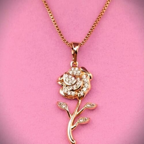 Επιχρυσωμένα Το Xuping Επιχρυσωμένo Κολιέ SKU 2G01 διαθέτει ένα χρυσό κρεμαστό κόσμημα σε σχήμα τριαντάφυλλου, διακοσμημένο με λαμπερά διαμάντια στα πέταλα, τα φύλλα και το στέλεχος, που εμφανίζονται όμορφα σε ροζ φόντο.